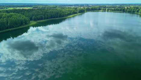 Lake-Laukezers,-Latvia-with-the-sky-reflecting-off-the-surface---aerial-view
