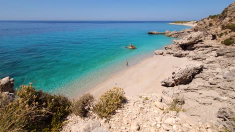 Summer-vacation-on-beautiful-beach-isolated-from-cliffs-and-blue-turquoise-sea-water-on-Mediterranean-seaside