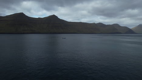 Luftaufnahme-Einer-Reise-In-Einem-Fischerboot,-Das-Durch-Einen-Fjord-Auf-Den-Färöer-Inseln-Fährt-Und-Von-Dem-Aus-Man-Die-Großen-Berge-Sehen-Kann
