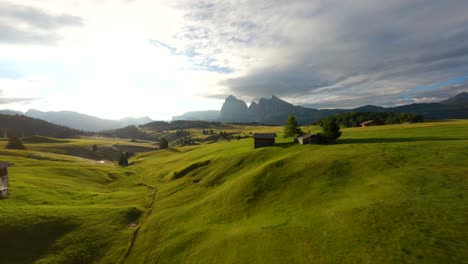Aerial-FPV-drone-footage-flying-fast-between-trees-and-cottages-in-the-plateau-of-Alpe-di-Siusi,-Seiser-Alm,-Dolomites-mountains,-Italian-Alps