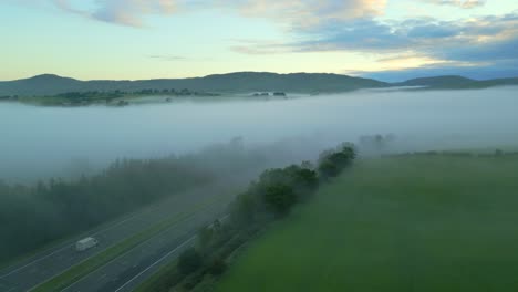 Mist-shrouded-M6-motorway-with-slow-pan-showing-fog-bank-and-distant-mountains-at-sunrise