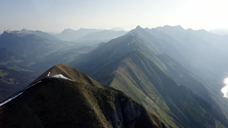 Hermosa-Cresta-Interminable-Entre-Enormes-Montañas-Y-Sobre-Un-Valle-Verde-Con-Un-Lago-Azul