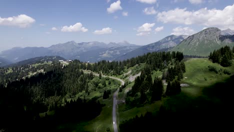 High-mountains-of-French-Alps-aerial-view-of-meandering-road-with-dark-shadow-play-and-car-on-meandering-road-in-the-foreground