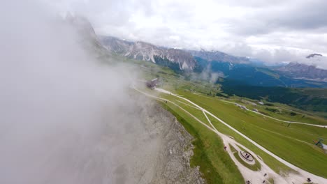 FPV-drone-flying-revealing-from-the-clouds-in-Seceda-mountain-ridge-located-in-Dolomite-Mountains,-Italian-Alps