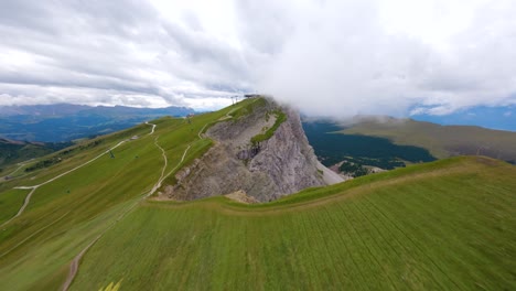 FPV-drone-footage-of-meadows-by-a-huge-mountain-cliff-in-Seceda,-in-Dolomites-natural-park-in-the-Italian-Alps