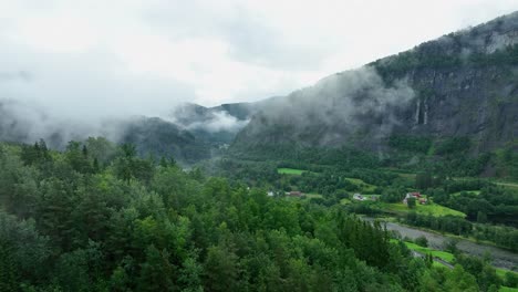 Flying-above-the-treetops-at-Bolstad-Norway---Foggy-morning-aerial-with-Vosso-river-in-bottom-of-valley
