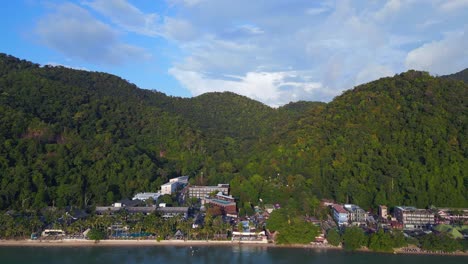 Stunning-aerial-top-view-flight-Beach-Village-Huts-Resort,-tropical-Bungalows-on-Mountainous-Island-Thailand-2022