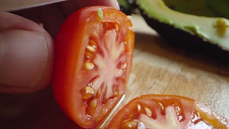 Eine-Kleine-Tomate-Wird-In-Zeitlupe-Mit-Einem-Messer-Auf-Einem-Schneidebrett-Geschnitten
