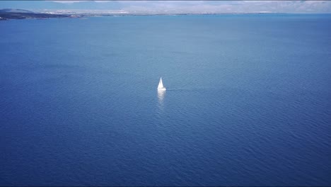 Wunderschöne-Aufnahmen-Eines-Weißen-Segelboots-Auf-Türkisfarbenem-Wasser-Mit-Blick-Auf-Die-Berge-Am-Horizont