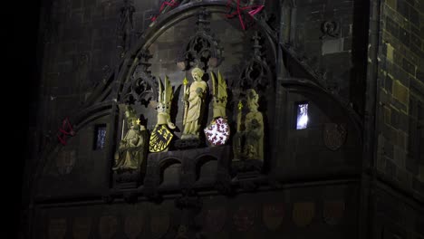 Charles-bridge-in-Prague,-Czech-Republic-in-the-night-close-up-on-the-Christian-religious-sculptures-with-golden-details-that-are-lighten-up-with-the-eagle-and-lion-emblem-representing-Czechia