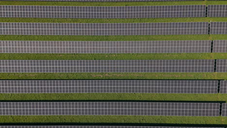 Volar-Sobre-Una-Enorme-Planta-De-Energía-Solar-Con-Múltiples-Paneles-Solares-En-Una-Colina-Verde-En-Alemania,-Energía-Renovable,-Imágenes-Aéreas