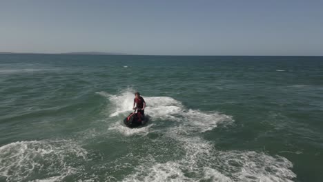 Jet-ski-rider-jumps-ocean-surf-waves-at-river-mouth,-Noosa-Heads-QLD