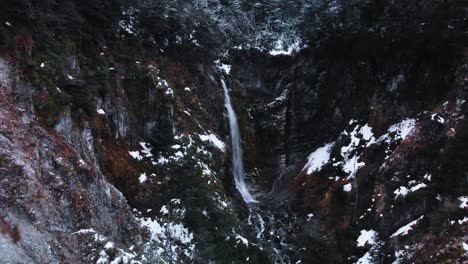 Eine-Ruhige-Luftaufnahme-Eines-Winterlichen-Bergwaldes-Mit-Einem-Wasserfall,-Der-Durch-Die-Landschaft-In-Patagonien-Fließt