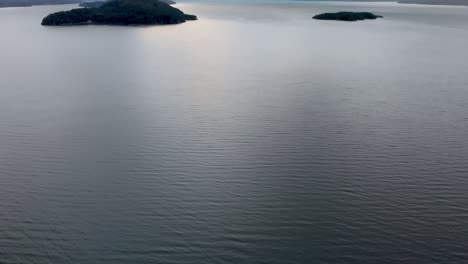 Eine-Atemberaubende-Luftaufnahme-Eines-Ruhigen-Patagonischen-Sees,-Dessen-Kristallklares-Wasser-In-Der-Wintersonne-Glitzert-Und-Der-Von-Majestätischen-Schneebedeckten-Bergen-Umgeben-Ist,-Die-Eine-Beeindruckende-Natürliche-Leinwand-Bilden