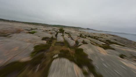 Low-flight-over-red-rock-terrain-of-Ramsvik-coast-in-Sweden