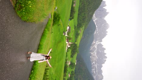 Woman-in-a-white-dress-and-a-hat-enjoys-the-landscape-of-Val-di-Funes,-Italy