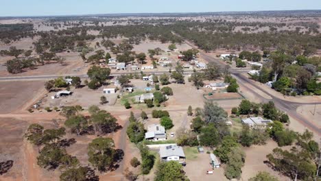 Aerial-view-of-a-very-small-town-in-the-outback-of-Australia,-showing-roads-and-homes-below