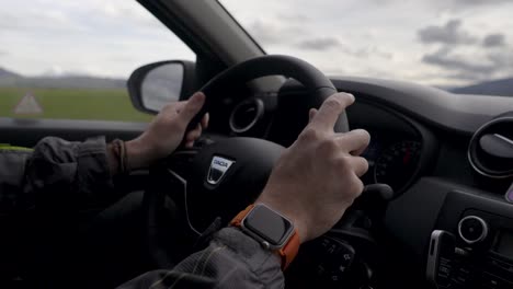 Un-Hombre-Conduciendo-El-Coche-Mientras-Conducía-Por-Un-Paisaje-Escénico-En-Islandia,-Con-Las-Manos-En-El-Volante.