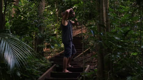 Static-shot-of-a-traveling-photographer-standing-on-a-wooden-staircase-in-the-jungle-while-taking-spectacular-shots-of-nature-during-an-adventurous-trip-from-norfolk-island-to-the-botanical-garden
