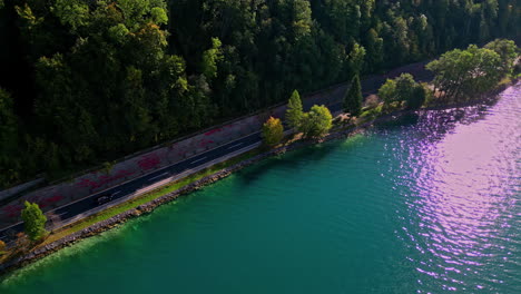 Drone-flying-along-the-shore-of-lake-Attersee-In-Austria-besides-a-thin-road