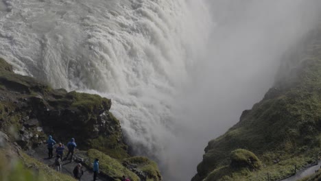 Tourists-standing-on-the-edge-of-the-majestic-waterfall-in-Iceland