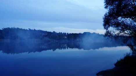 Dark-evening-near-the-lake-with-fog-in-a-blue-hour