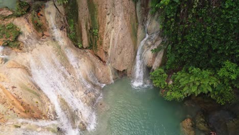 Descending-aerial-view-of-limestone-Kinahugan-waterfall,-Philippines