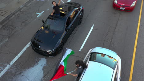People-rising-out-from-their-cars-to-wave-Palestine-flags-to-protest-in-USA---Aerial-view