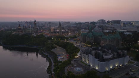 Reversing-drone-shot-of-downtown-Ottawa-in-the-early-morning,-showing-the-city-skyline-including-the-justice-building,-the-peace-tower-and-the-supreme-court