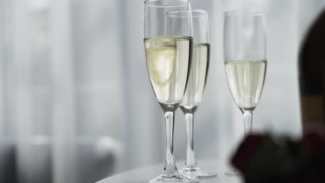 Close-up-of-elegant-bubbly-champagne-flute-glasses-on-a-white-wedding-table