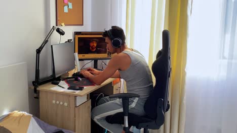 Shot-of-a-young-man-wearing-grey-track-suit-and-typing-on-keyboard-of-a-computer-inside-a-room