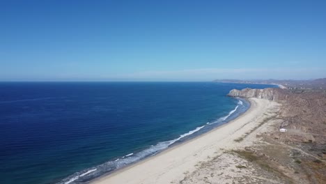 Aerial-dolly-shot-from-the-idyllic-beach-of-cabo-san-lucas-in-baja-california-sur,-mexico-overlooking-the-picturesque-coastline-with-blue-sea,-secluded-beach-and-dry-landscape-on-a-sunny-day