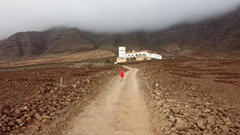 Mujer-Vestida-De-Rojo-Caminando-Hacia-La-Casa-Museo-De-Invierno-En-Fuerteventura