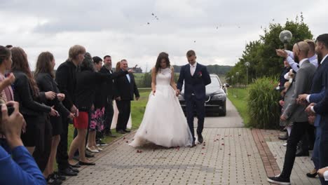 Wedding-guests-throw-rose-petals-at-young-newlywed-couple-as-a-tradition