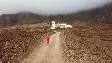 A-woman-in-a-red-dress-is-walking-down-a-small-road-from-Casa-Winter