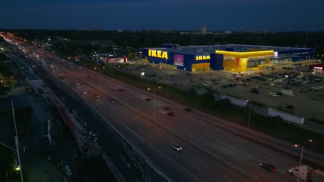 El-Tráfico-En-La-Autopista-417-En-Ottawa,-Canadá,-Pasa-Por-Una-Gran-Tienda-Ikea-Por-La-Noche.
