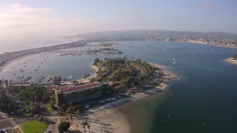 Cinematic-drone-view-of-Mission-Bay-in-San-Diego,-CA-with-ocean-and-mountains-in-background