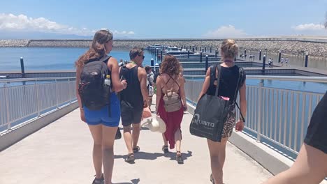 Tourists-walking-towards-the-ship-that-will-take-them-on-a-tour-to-Nusa-Penida-Island,-Bali,-Indonesia