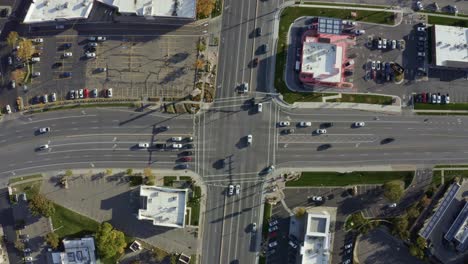Aerial-drone-bird's-eye-top-view-shot-of-a-busy-road-intersection-in-the-middle-of-a-business-center-surrounded-by-buildings-on-a-sunny-fall-day-in-Salt-Lake-county,-Utah