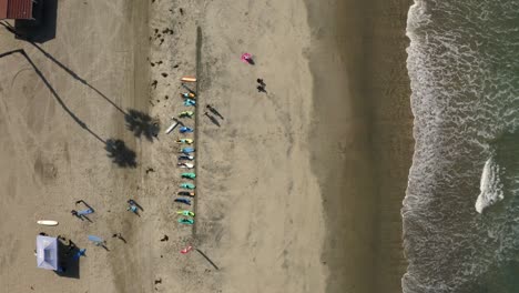 Down-facing-drone-view-of-a-group-of-Surfers-in-San-Diego-waxing-their-surf-boards