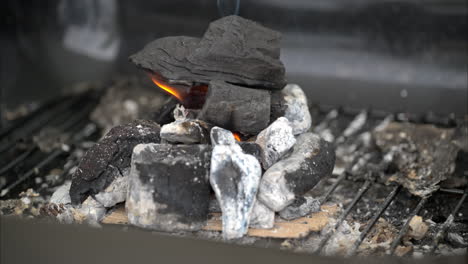 Slow-motion-close-up-of-a-pile-of-charcoal-starting-to-burn-with-a-little-flame-and-some-smoke