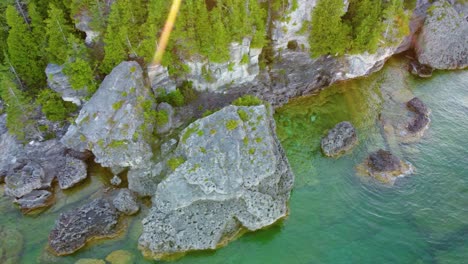 Aerial-view-of-seashore-with-rocky-terrain-with-forest-on-shore