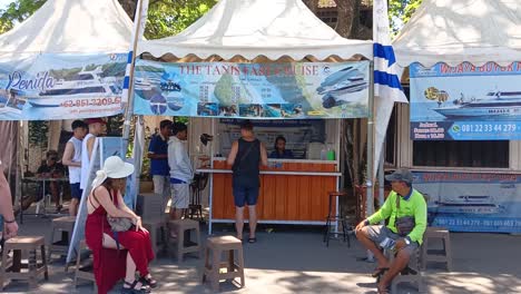 Tourists-stand-buying-tickets-for-a-fast-boat-that-will-take-them-on-a-trip-to-Nusa-Penida-Island,-Bali,-Indonesia