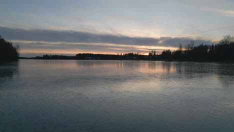 Puesta-De-Sol-Reflejada-En-El-Lago-Congelado-En-Suecia,-Vista-Frontal-De-La-Plataforma-Rodante