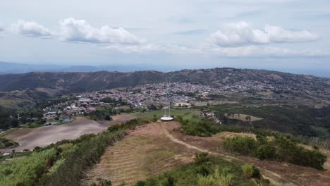 Visual-Aérea-Con-Drone-De-Una-Cruz-En-Una-Montaña-Y-Al-Fondo-El-Pueblo-De-Sarane,-Ubicado-En-El-Estado-De-Lara,-Venezuela