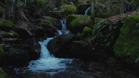 Forward-moving-super-slow-motion-shot-of-a-water-basin-and-a-creek-waterfall-in-background