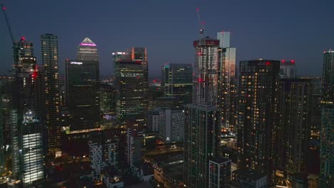 Vista-Aérea-A-Través-Del-Icónico-Futurista-Canary-Wharf-Londres-Paisaje-Urbano-De-Gran-Altura-Rascacielos-Iluminados-En-El-Crepúsculo