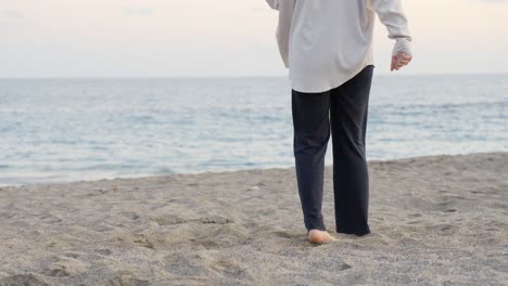 Person-dancing-barefoot-in-slow-motion-on-warm-sandy-beach,-medium-shot
