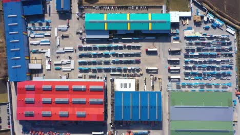 Aerial-view-of-a-semi-trucks-with-cargo-trailers-standing-on-warehouses-ramps-for-loading-unloading-goods-on-the-big-logistics-park-with-loading-hub