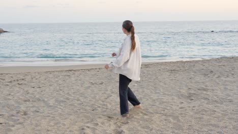 Woman-dancing-alone-barefoot-on-sand,-practising-next-to-shore,-slowmo